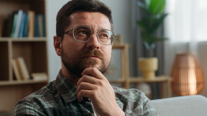 Portrait pensive thinking hesitate unsure think thoughtful confused puzzled Caucasian man male guy come up with idea finding answer creative solution insight smiling looking at camera at home indoors