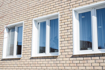 Exterior brick wall with four white-framed windows under clear blue sky