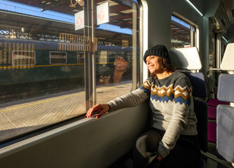 Passenger enjoying a scenic train ride, with a window view of the station platform.