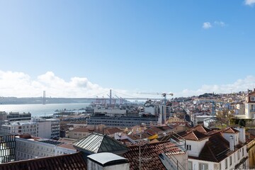 Panorama of Lisbon with tiled roofs and yellow construction crane in the old town. Tiled roofs of Lisbon are visible from the observation deck