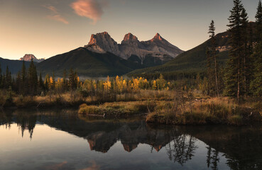 Scenery of Three Sisters Mountains reflection on autumn forest in the morning at Canmore, Banff national park