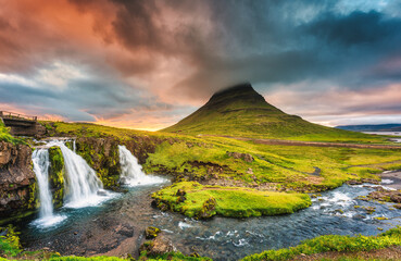 Landscape of sunset over Kirkjufell mountain with Kirkjufellsfoss waterfall and colorful pileus cloud on summer at Iceland