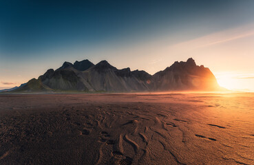 Golden sunrise on Vestrahorn mountain by atlantic ocean and black sand beach in the morning at...