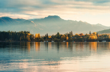 Sunrise over mountain range and autumn forest on Lake Wanaka