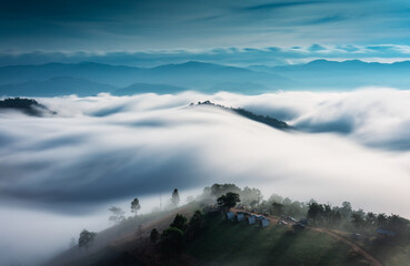 Landscape of sea of fog flowing over mountain with homestay on hill in countryside at Mae Jam, Chiang Mai