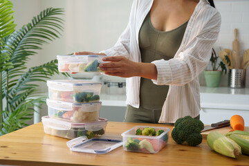 Beautiful young woman preparing healthy meal in clear plastic storage boxes. Nutritious and healthy...