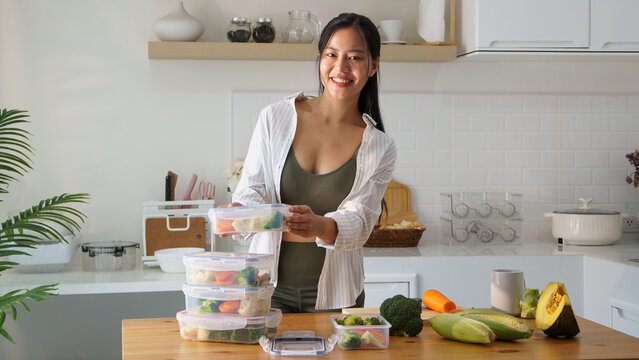 Beautiful young woman preparing healthy meal in clear plastic storage boxes. Nutritious and healthy lifestyle concept.