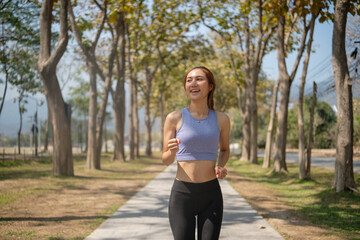 Beautiful woman jogging along a peaceful park pathway. Fitness and healthy lifestyles concept.