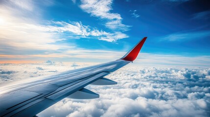 Fototapeta premium A stunning view of an airplane wing above the clouds, with a brilliant blue sky and a few wispy clouds below.
