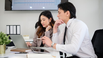 Fototapeta premium A male and female colleague work together on a project, concentrating on important data displayed on a laptop.