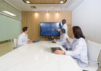Medical professional engaged in a collaborative meeting discussing research finding and patient care strategy in a modern conference room