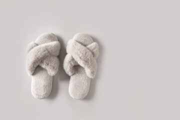 Pair of soft gray female slippers for home on gray background. View from above. Copy space.