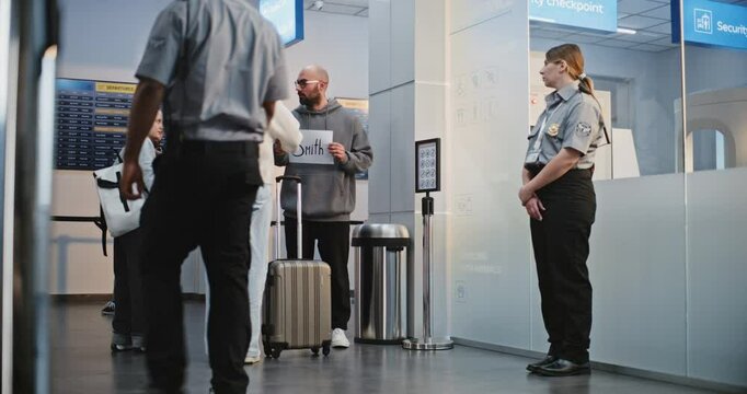 International Airport Terminal: Airport Greeter Holding Name Sign, Meeting Passengers From Plane Flight. Diverse People Walking with Luggage. Business Transfer or Transportation Service. Full Shot.