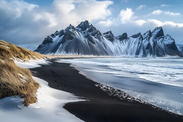 Majestic snow-capped mountain range towering over a black sand beach at dusk in Iceland