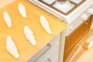a tray of croissants in a home kitchen. making croissants at home. homemade baked goods. unbaked croissant. uncooked croissant. baking oven