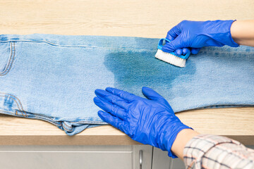 man cleaning jeans from dirt with a brush. woman removing dirty stain on jeans, close-up. removing...