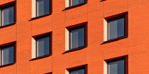Obraz premium Modern urban building facade with vibrant orange bricks and symmetrical windows, showcasing contemporary architecture