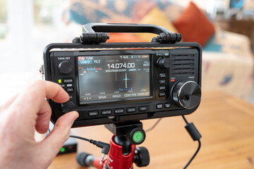 Portable Japanese-built amateur radio HF transceiver seen being operated by a radio ham. The screen...