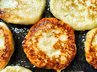 Delicious golden-brown potato pancakes being cooked on a frying pan with oil