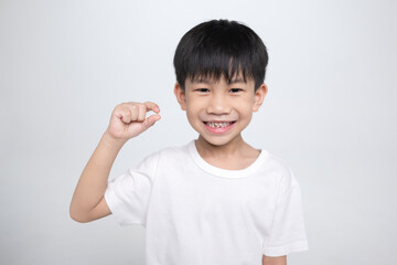 6 years old Asian boy showing his lost tooth, proud of his gap.