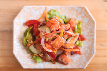 Spicy salmon salad with vegetables on a decorative plate.