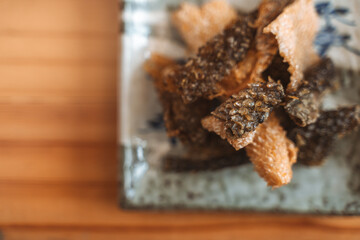 Crispy fried fish skin served on a decorative ceramic plate as a snack or appetizer.