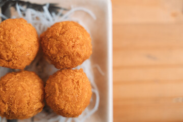 Golden crispy croquettes on a ceramic plate with shredded garnish.