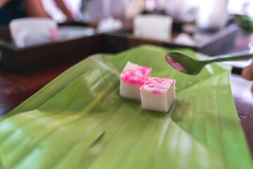 Traditional Thai coconut jelly with pink topping served on a banana leaf, highlighting vibrant local cuisine.