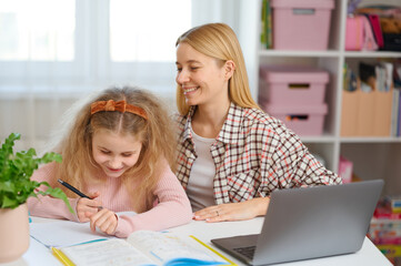 Mother and daughter sit at desk with laptop, solving homework questions together. Engaging home study moment, school preparation with family support