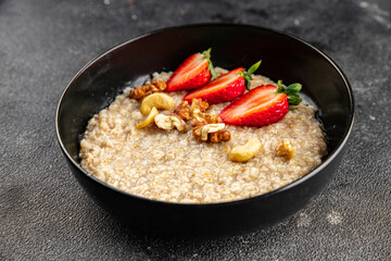 Oatmeal porridge with strawberries and nuts healthy breakfast appetizer dish fresh gourmet food background on the table rustic food top view copy space keto and paleo diet vegetarian and vegan food