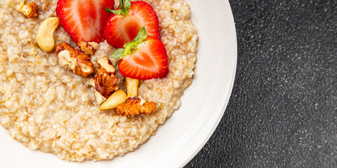 Oatmeal porridge with strawberries and nuts healthy breakfast appetizer dish fresh gourmet food background on the table rustic food top view copy space keto and paleo diet vegetarian and vegan food