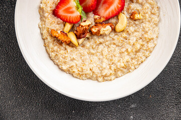 Oatmeal porridge with strawberries and nuts healthy breakfast appetizer dish fresh gourmet food background on the table rustic food top view copy space keto and paleo diet vegetarian and vegan food
