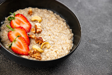 Oatmeal porridge with strawberries and nuts healthy breakfast appetizer dish fresh gourmet food background on the table rustic food top view copy space keto and paleo diet vegetarian and vegan food