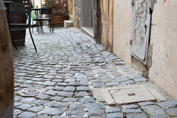 Fototapeta premium A charming cobblestone street has a manhole cover in the middle