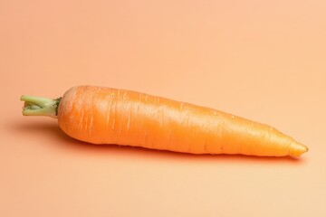A single orange carrot lies on a smooth peach colored background