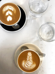Cafe. Flat White Coffee with Latte Art, Glasses of Water Served for Two on White Marble Cafe Table. 