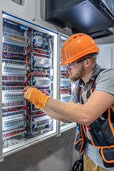 Male electrician working in electrical panel. Male electrician in overalls.
