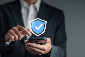 Data protection and information security system concept. Cybersecurity, internet network security. Businessman using smartphone with shield and checkmark icon on virtual screen.