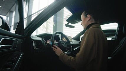  A satisfied, happy woman client sitting behind the wheel of a new car. Concept a joyful moment of car ownership, highlighting the excitement and satisfaction of a new purchase.