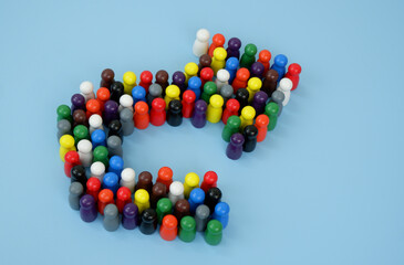 Many wooden people figures shaped as turn arrow on blue background. Changing people mind concept.