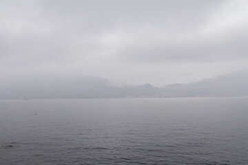 A serene and mystical image of Lake Como shrouded in early morning fog.