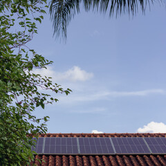 Solar panels on the red roof in a sunny and cloudy day. Photovoltaic instalation image.