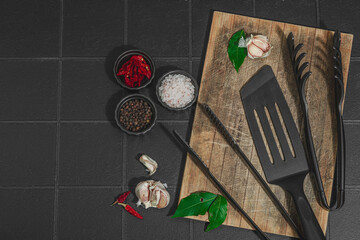 Barbecue season concept. Grill tongs, spatula, spices set, coarse salt, garlic and fresh herbs