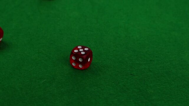 Red dice falling onto a green casino mat, close-up