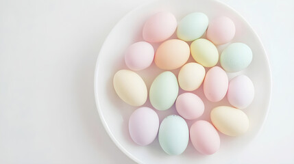 Fototapeta premium Pastel colored eggs arranged on a white plate with soft natural lighting and minimal background. Copy space