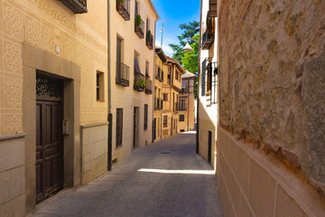 Calle estrecha del centro histórico de Segovia, España, con fachadas tradicionales y balcones adornados.