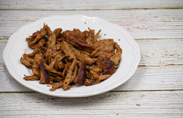 Shredded seitan, mock chicken, on white plate, wooden table. Copy space.