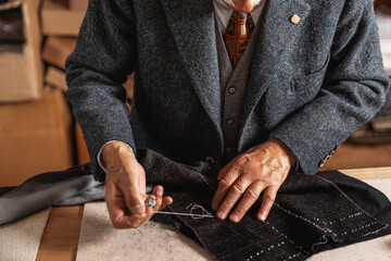 Fototapeta premium A charismatic tailor, deeply focused on his craft. His skilled hands carefully stitch fabric. A master of traditional handcraftsmanship, dedicated to every detail. Handcrafting in a sewing atelier