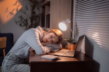 Obraz premium Young Asian office worker sleeping on desk at night after working late with laptop, calculator and notebook, tired businesswoman resting after long working hours