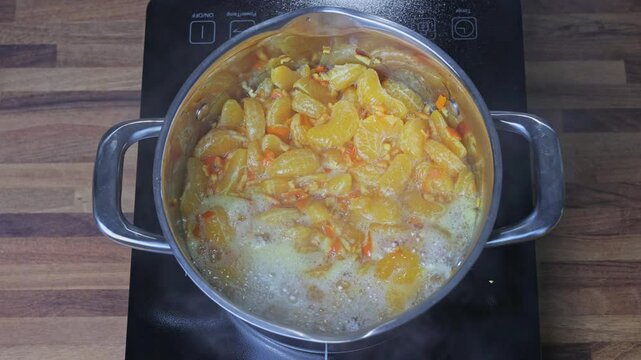 Cooking tangerine jam in a saucepan on the stove in a home kitchen